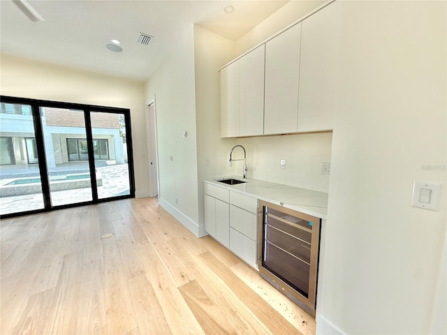 807 N Flagler Ave, Flagler Beach, FL 32136 - bar featuring wine cooler, a sink, baseboards, and light wood-type flooring