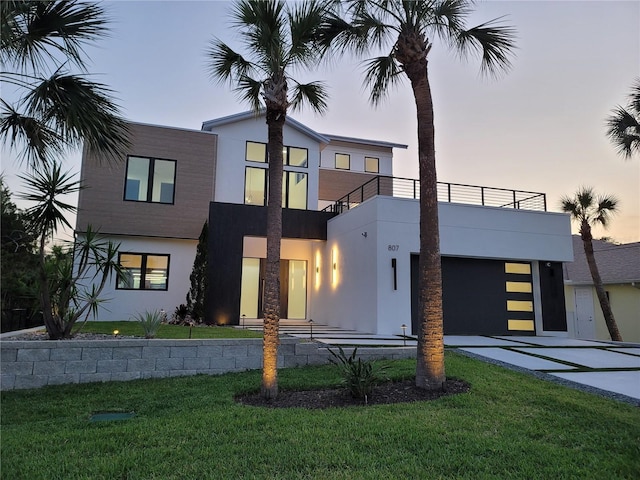 807 N Flagler Ave, Flagler Beach, FL 32136 - contemporary home featuring a balcony, driveway, stucco siding, a front yard, and a garage
