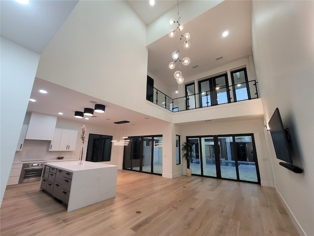 807 N Flagler Ave, Flagler Beach, FL 32136 - kitchen with high vaulted ceiling, open floor plan, light wood finished floors, white cabinets, and decorative light fixtures