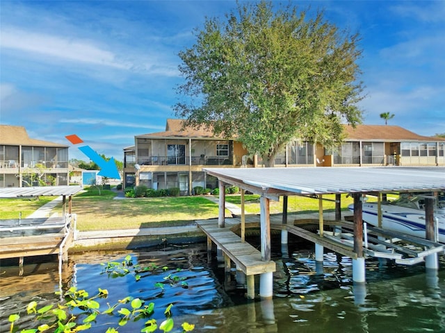 dock with boat lift, a water view, a lawn, and a balcony