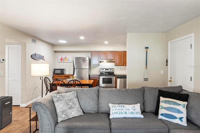 living room with light wood-style floors, recessed lighting, and baseboards