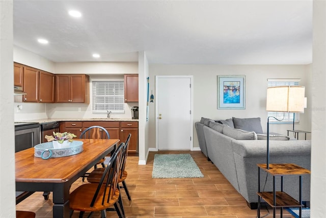 kitchen with under cabinet range hood, stove, light wood-style flooring, light countertops, and open floor plan
