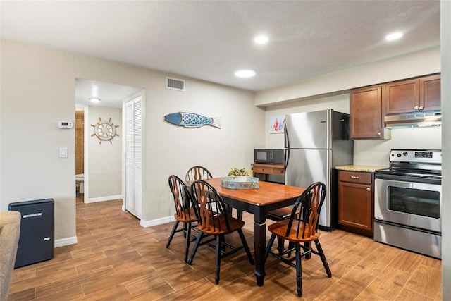 kitchen featuring appliances with stainless steel finishes, under cabinet range hood, light wood-style floors, baseboards, and recessed lighting