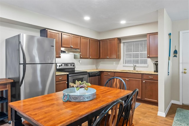 kitchen featuring appliances with stainless steel finishes, under cabinet range hood, a sink, light wood-style floors, and light countertops