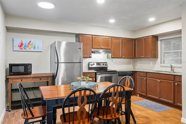 kitchen featuring appliances with stainless steel finishes, under cabinet range hood, a sink, light wood finished floors, and recessed lighting