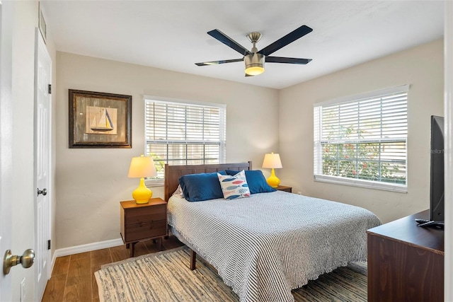 bedroom featuring multiple windows, wood finished floors, baseboards, and a ceiling fan