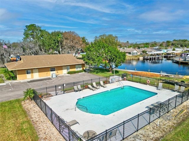 community pool featuring a water view, fence, and a patio