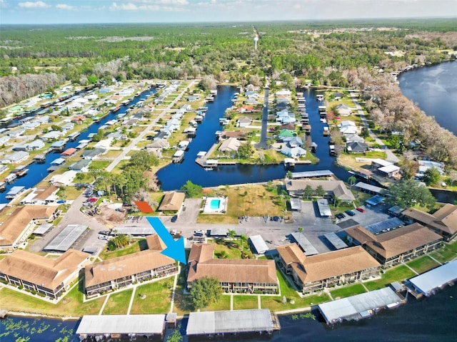 aerial view of property's location featuring a nearby body of water, a heavily wooded area, and nearby suburban area