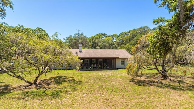 486 S US Highway 1, Oak Hill, FL 32759 - rear view of house with a yard, a sunroom, and a chimney