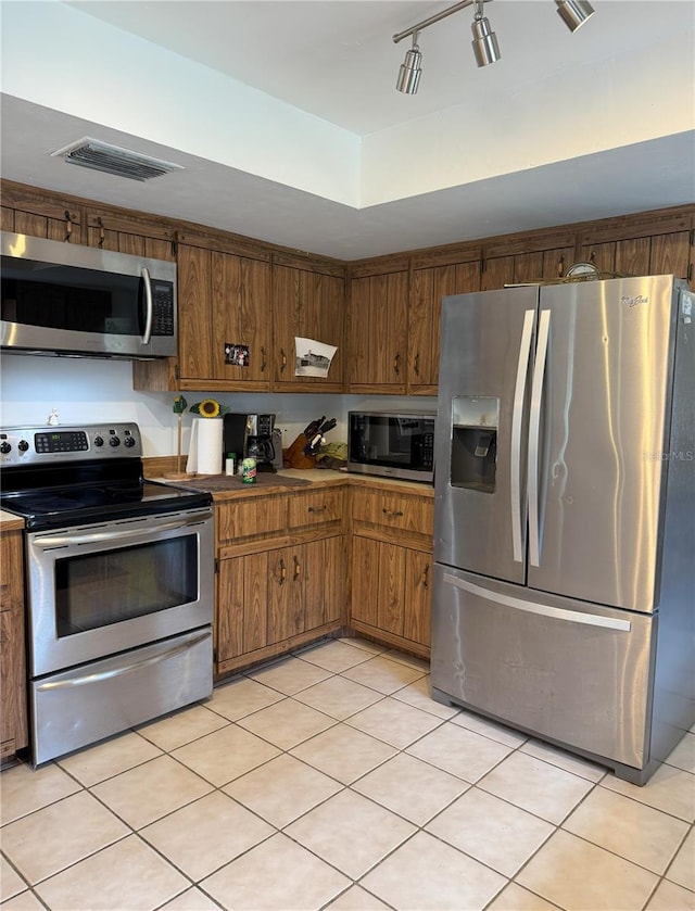 486 S US Highway 1, Oak Hill, FL 32759 - kitchen with appliances with stainless steel finishes, light tile patterned flooring, and brown cabinetry