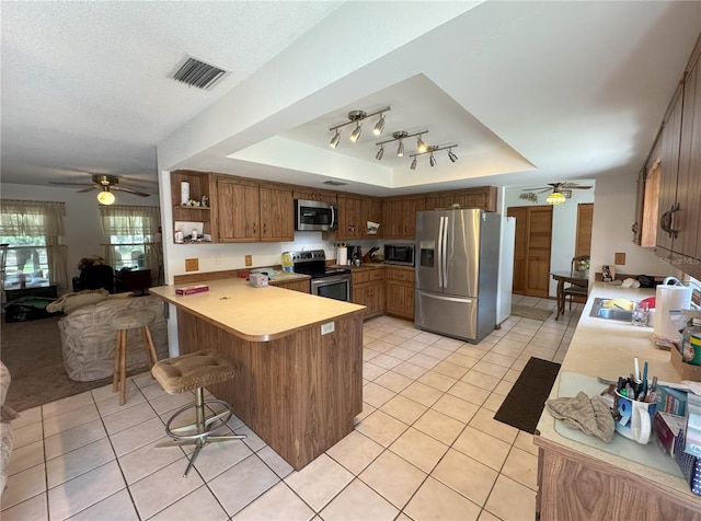486 S US Highway 1, Oak Hill, FL 32759 - kitchen featuring appliances with stainless steel finishes, a tray ceiling, a peninsula, and ceiling fan