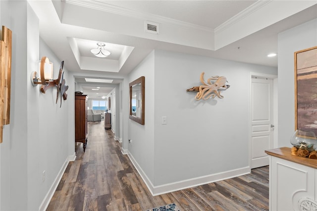 corridor featuring a tray ceiling, dark wood-style floors, baseboards, crown molding, and recessed lighting