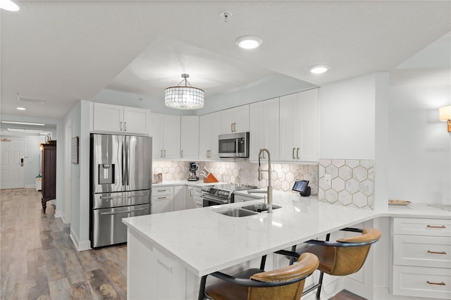 kitchen featuring appliances with stainless steel finishes, white cabinets, wood finished floors, a peninsula, and recessed lighting