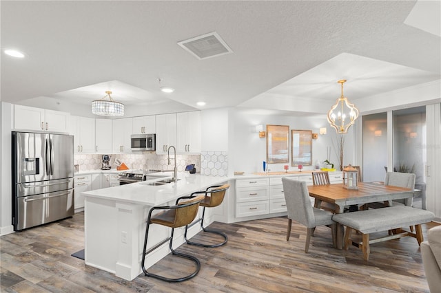 kitchen with stainless steel appliances, a chandelier, a peninsula, dark wood-type flooring, and recessed lighting