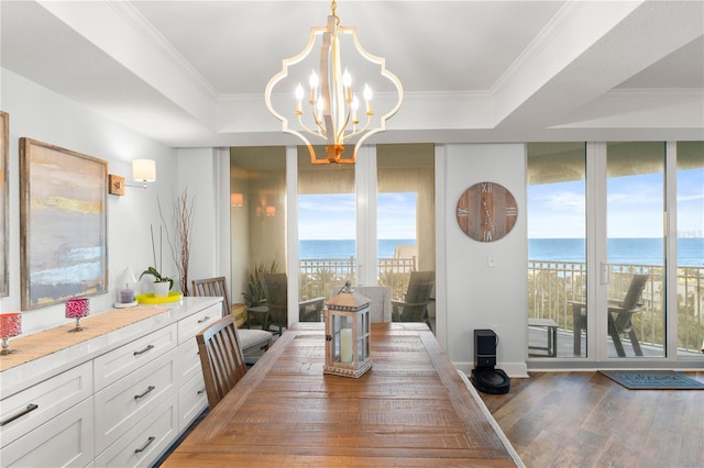 dining space with a water view, light wood-style flooring, a chandelier, and ornamental molding