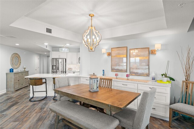 dining room with a tray ceiling, dark wood-style floors, crown molding, a chandelier, and recessed lighting