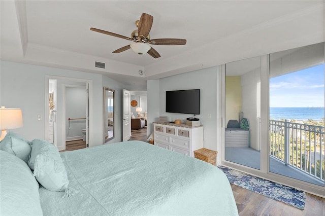 bedroom featuring wood finished floors, access to exterior, a tray ceiling, ceiling fan, and baseboards