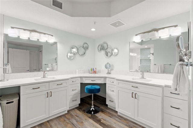 bathroom with a stall shower, wood finished floors, and two vanities