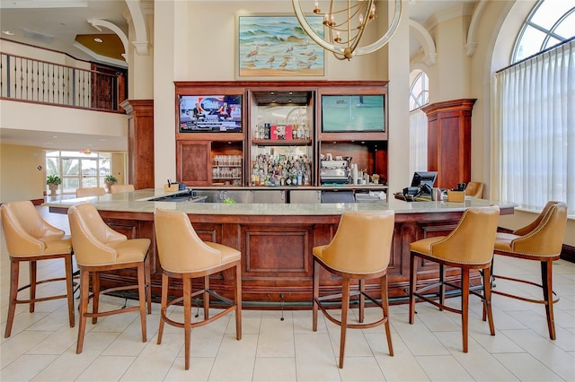 indoor dry bar featuring a towering ceiling, a chandelier, and crown molding
