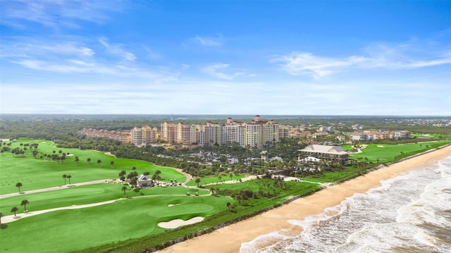 aerial view of waterfront with a beach, apartment complex / building, and a golf course