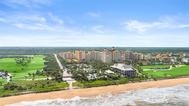 bird's eye view of expansive beach, apartment complex / building, and a local golf course