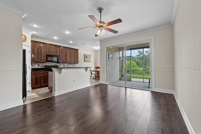 70 Riverview Bnd S Unit 715, Palm Coast, FL 32137 - kitchen with black appliances, ornamental molding, a kitchen breakfast bar, dark countertops, and ceiling fan