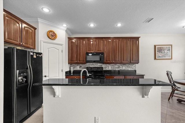 70 Riverview Bnd S Unit 715, Palm Coast, FL 32137 - kitchen with black appliances, tasteful backsplash, a breakfast bar, an island with sink, and a textured ceiling