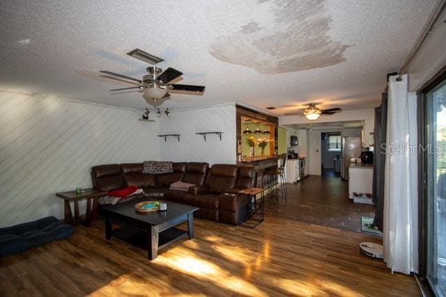 living area with a ceiling fan, wood finished floors, and a textured ceiling