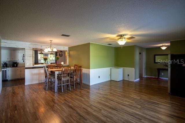 dining room featuring a chandelier, dark wood finished floors, a ceiling fan, and a textured ceiling