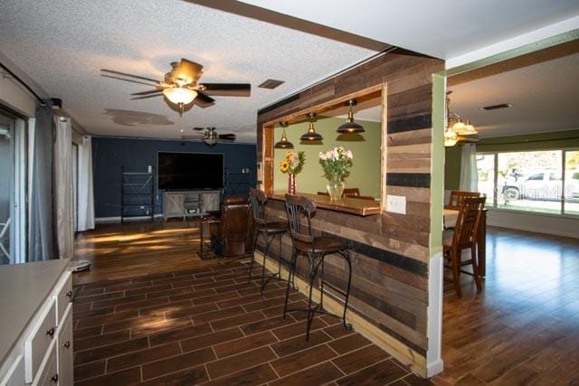 dining space featuring dark wood-style floors, a ceiling fan, and a textured ceiling