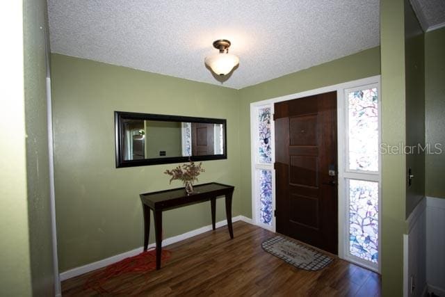 foyer with wood finished floors, a textured ceiling, and baseboards
