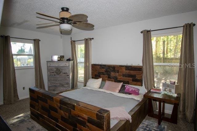 bedroom with multiple windows, carpet floors, a textured ceiling, and ceiling fan