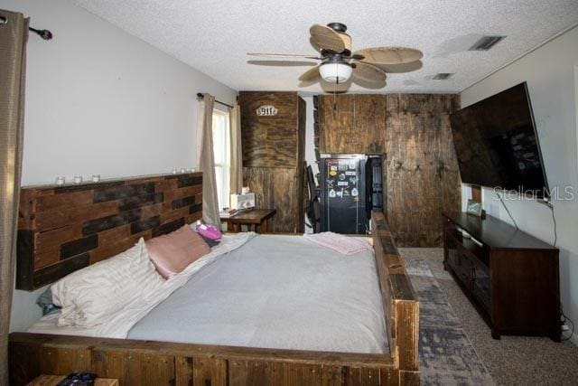 bedroom featuring a textured ceiling, wood walls, and carpet floors