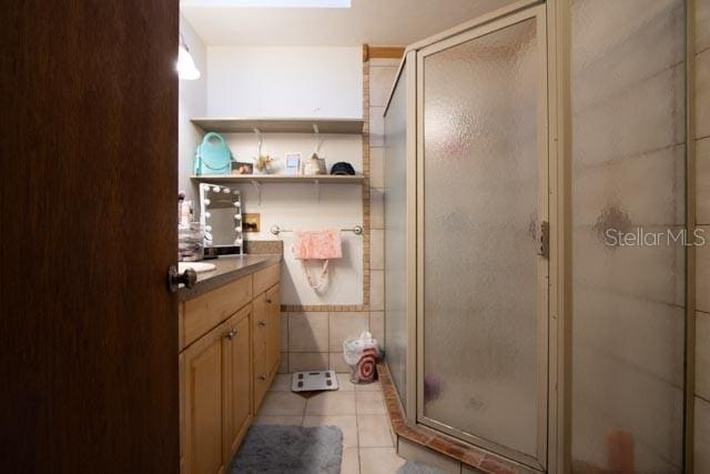 bathroom with tile patterned floors, a stall shower, vanity, and tile walls