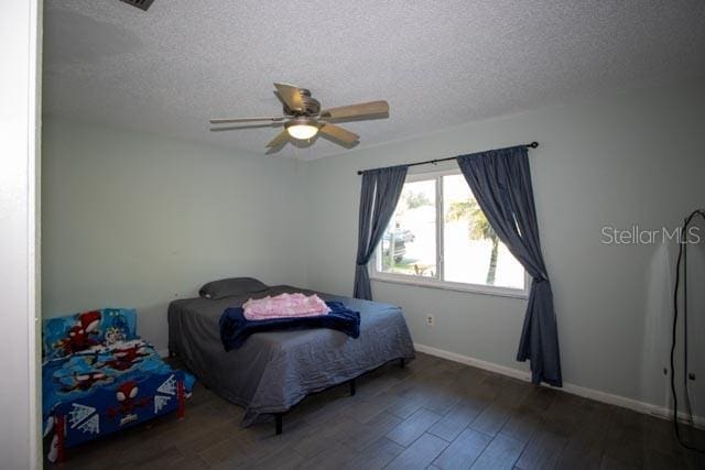 bedroom featuring a textured ceiling, wood finished floors, baseboards, and a ceiling fan