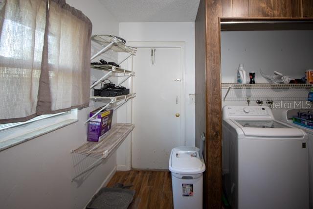 clothes washing area with washer / dryer, wood finished floors, and a textured ceiling