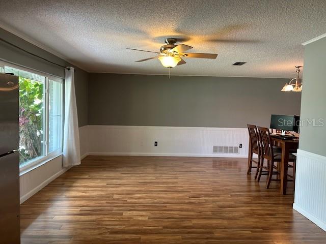 1 Belvedere Ln, Palm Coast, FL 32137 - empty room with wood finished floors, a textured ceiling, ceiling fan, a chandelier, and a wainscoted wall