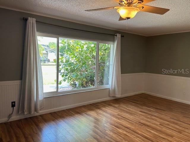 1 Belvedere Ln, Palm Coast, FL 32137 - unfurnished room featuring wood finished floors, a wainscoted wall, ceiling fan, and a textured ceiling