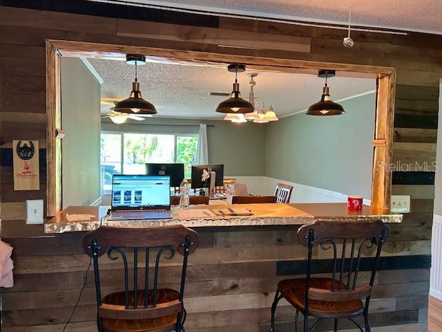 1 Belvedere Ln, Palm Coast, FL 32137 - indoor dry bar with decorative light fixtures, a textured ceiling, wood finished floors, wooden walls, and a ceiling fan