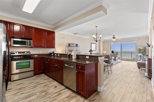 kitchen with appliances with stainless steel finishes, a sink, dark brown cabinets, a peninsula, and crown molding
