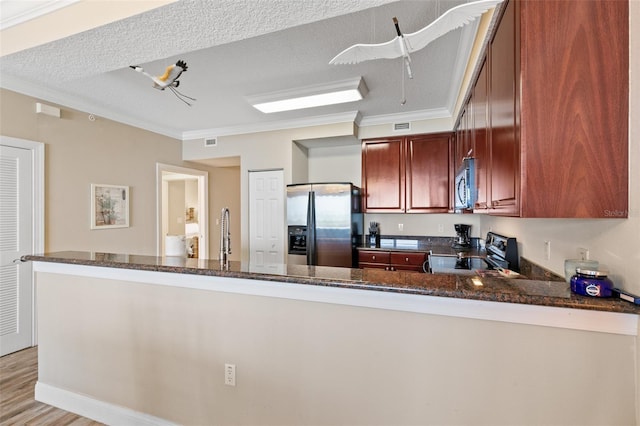 kitchen with appliances with stainless steel finishes, ornamental molding, dark stone countertops, a textured ceiling, and light wood-style flooring