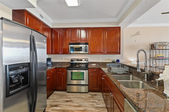 kitchen featuring stainless steel appliances, a sink, crown molding, light wood-style flooring, and dark brown cabinets