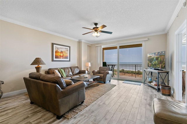 living room with wood finished floors, a ceiling fan, a textured ceiling, ornamental molding, and baseboards