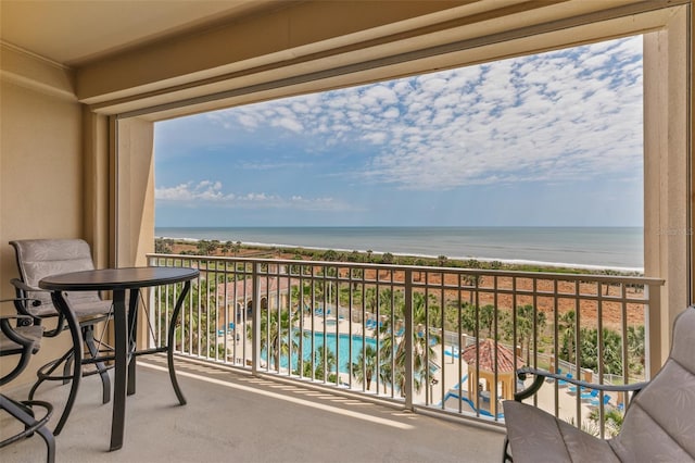 balcony with view of pool and view of water and beach