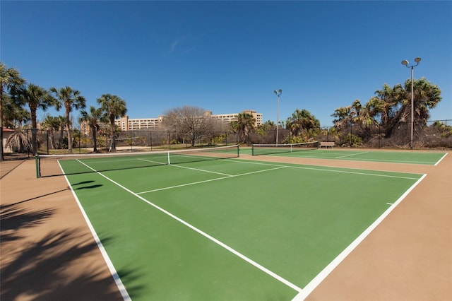 view of tennis court with community basketball court and fence