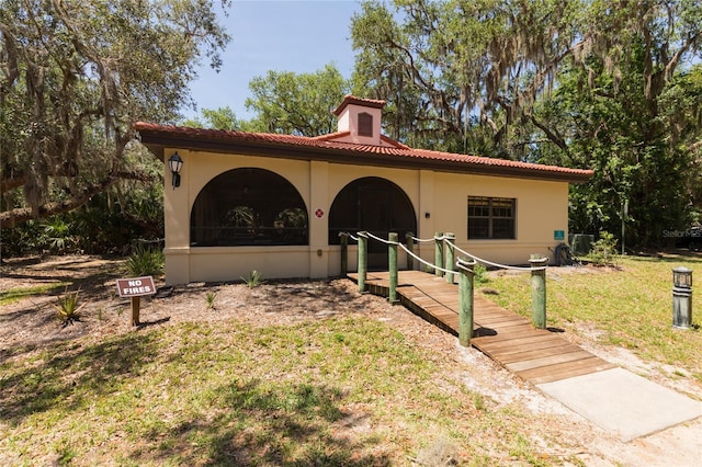 mediterranean / spanish house with a front yard, a tile roof, and stucco siding