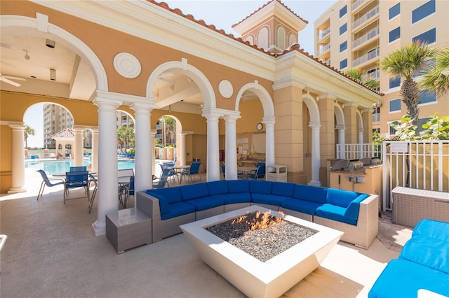 view of patio with an outdoor living space with a fire pit, a community pool, a grill, and exterior kitchen