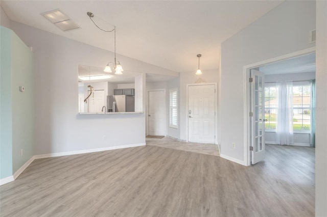 613 Clairmont Ln, South Daytona, FL 32119 - unfurnished living room with lofted ceiling, light wood-type flooring, baseboards, and a chandelier