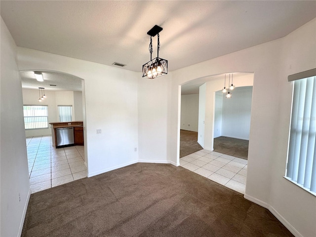 15 Ruth Dr, Palm Coast, FL 32164 - unfurnished dining area with tile patterned floors, arched walkways, carpet flooring, and a chandelier