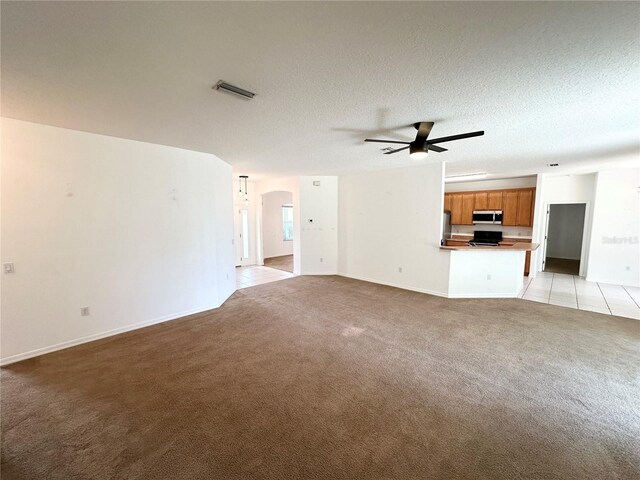 15 Ruth Dr, Palm Coast, FL 32164 - unfurnished living room with light colored carpet, ceiling fan, baseboards, arched walkways, and a textured ceiling